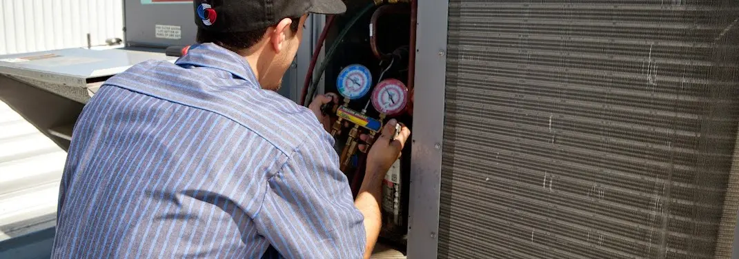 HVAC technician servicing a condenser unit in Breitung